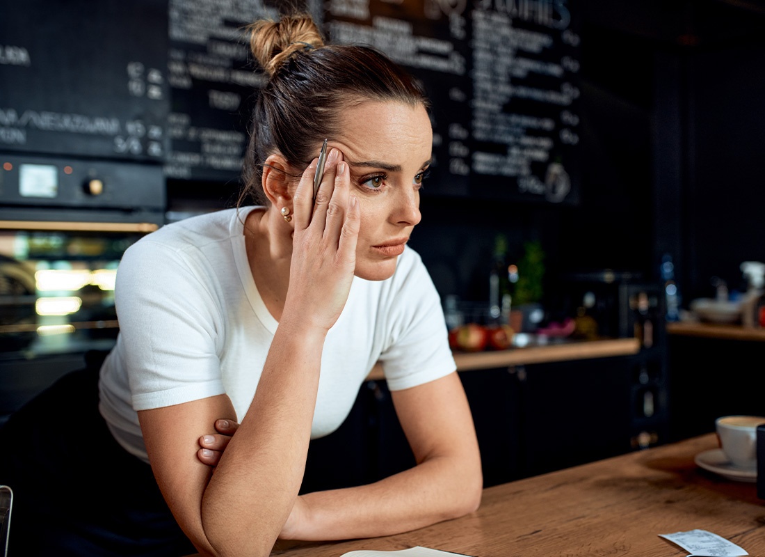 Business Interruption Insurance - Portrait of a Frustrated Small Business Owner Standing at the Counter of Her Closed Cafe