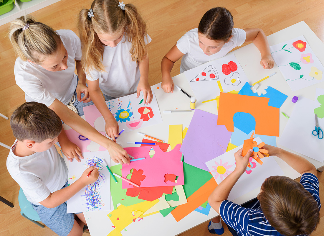 Business Insurance - Overhead View of a Teacher With Her Students Working on an Art Assignment