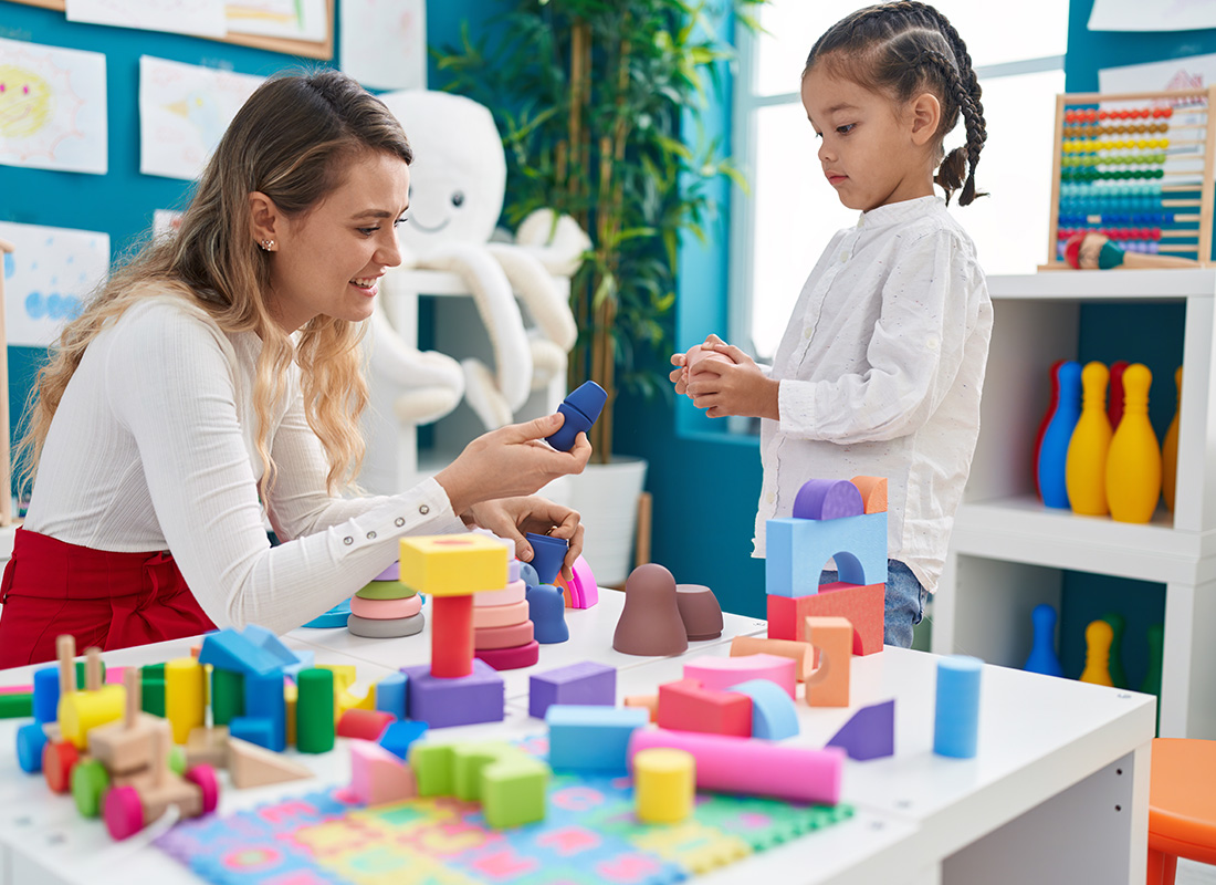 Insurance by Industry - Preschool Teacher Helping a Young Student Build With Blocks